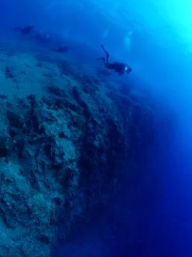 Scuba divers exploring rocks and reef underwater scenery Stock Photos