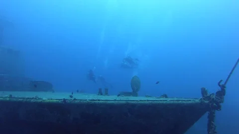 SCUBA divers exploring underwater wreck Stock Footage 128848678