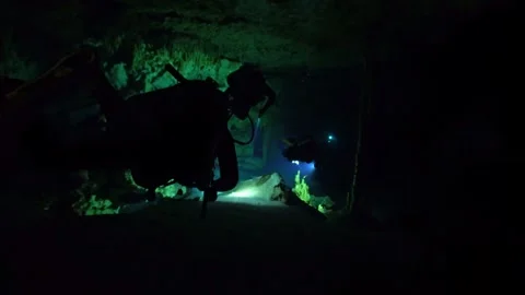 Scuba divers with flashlights exploring underwater cave Stock Footage 330547338
