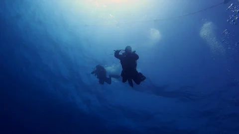 Scuba divers. Rays sun shine silhouette. 4k Stock Footage 129094122
