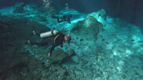 Scuba divers swim in crystal clear cenote Mexico Yucatan Sun Rays ambient sound Stock Footage 253216563