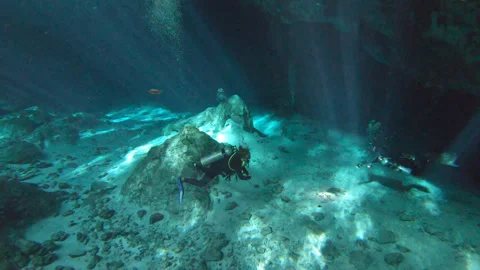 Scuba divers swim in crystal clear cenote Mexico Yucatan Sun Rays ambient sound Stock Footage 253220979
