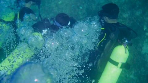 Scuba divers swimming in group, with bubbles rising to surface from above Stock Footage 241086182