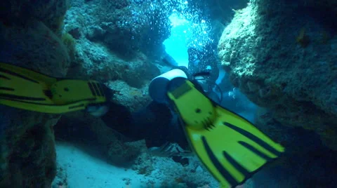 Scuba divers swimming through cave Stock Footage 2256353