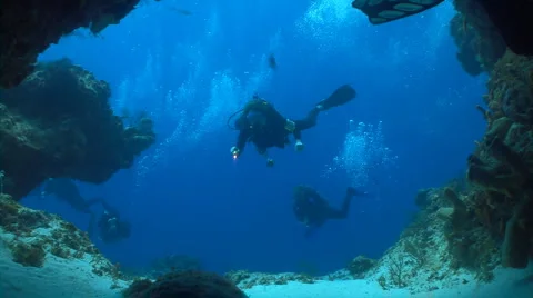 Scuba divers swimming through cave Stock Footage 2659093