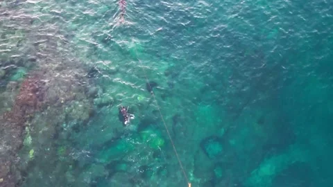 Scuba diving in the blue sea. Divers underwater. Drone footage. Rocky beach. Stock Footage 233595488