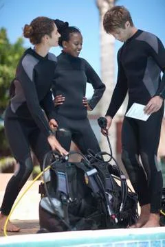 Scuba diving instructor and pupils with scuba tanks Stock Photos