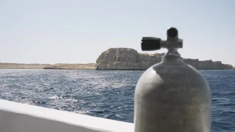 Scuba tank standing on a boat deck sailing on the blue sea towards a rocky Stock-Footage 333848632