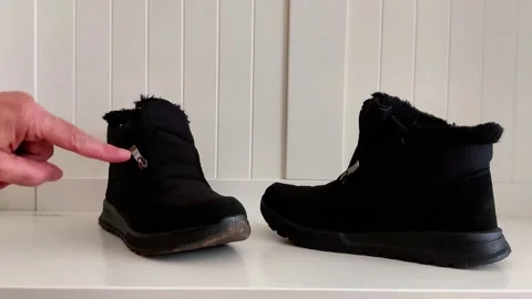 Scuffed vs. Pristine Black Winter Boots on White Studio Surface 스톡 동영상 321518270