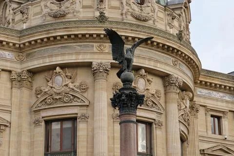 Sculpted eagle perched on column against ornate building facade in European.. Stock Photos
