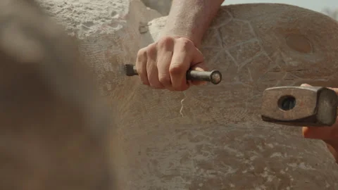 Sculptor hands carving stone block with chisel and hammer close up in Piran Stock Footage 341461483