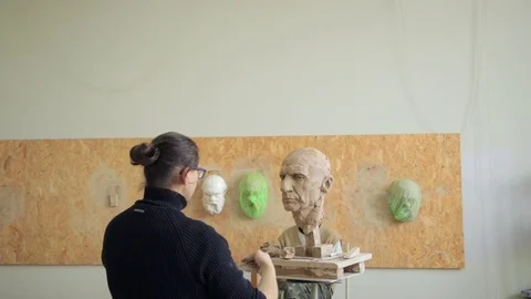 Sculptor modelling sculpture adjusting face details head made of clay Stock Footage