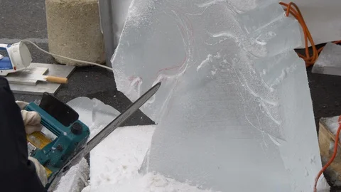 Sculptor uses a chisel and chain saw to carve ice1 4K 動画素材 101447011