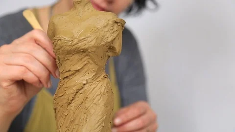 Sculptor Uses Tool To Sculpt Side Of Clay Statue. A sculptor creates a sculpture Stock Footage 90796332