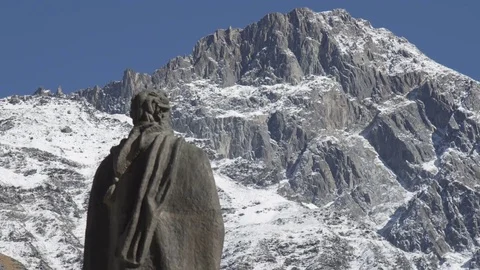 Sculpture of anonymous in front of snow covered top of the mountain Видео 81877015