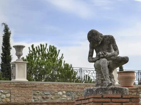 Sculpture of a boy sitting while removing a thorn from the sole of his left f Fotos de archivo