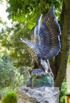 Sculpture of an eagle made of stone on the background of green trees Stock Photos