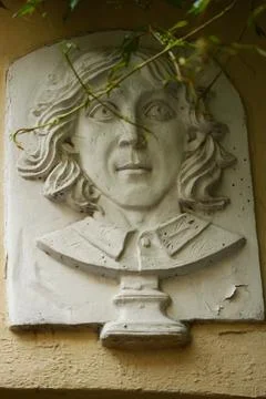 A sculpture of a man's face is embedded in the side of a building, creating an Stock Photos