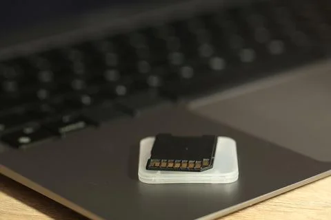 SD memory card, holder and laptop on wooden table, closeup Stock Photos
