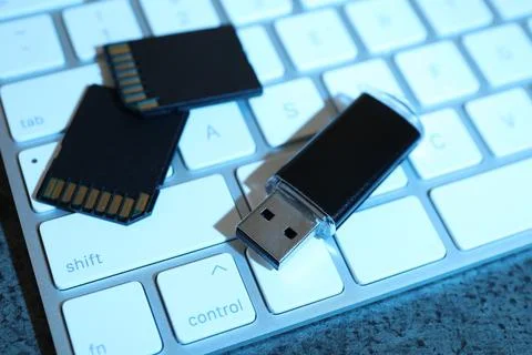 SD memory cards, USB flash drive and keyboard on dark grey table, closeup Stock Photos