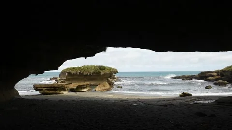 The sea and beach viewed from within a massive cavern in the cliff. Stock Footage 148448262