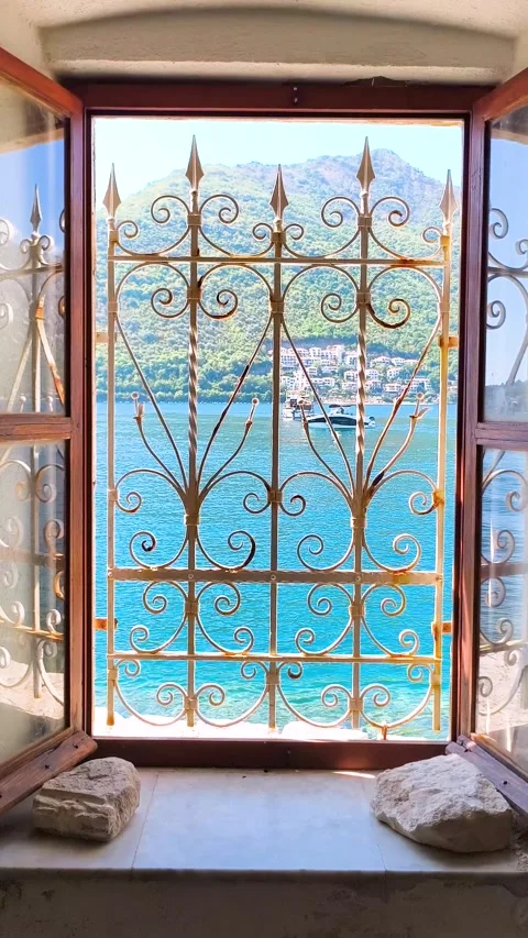 Sea and mountain view through decorative metal window grill Stock Footage 340533356