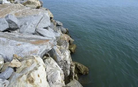 The sea is bordered by large breakwater rocks. sea and rock background Stock Photos