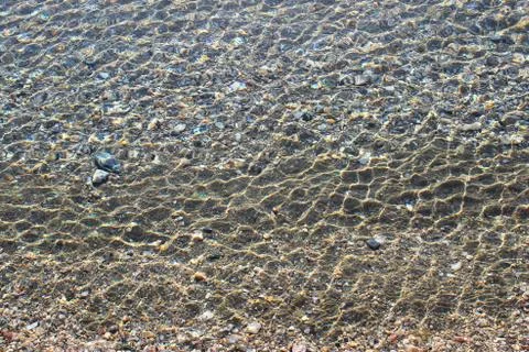 Sea bottom with pebbles through clear water Stock Photos