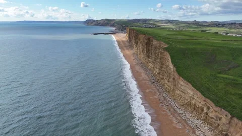 Sea cliffs on Devon coast UK drone aerial view red sand on beach Video stock 333623919