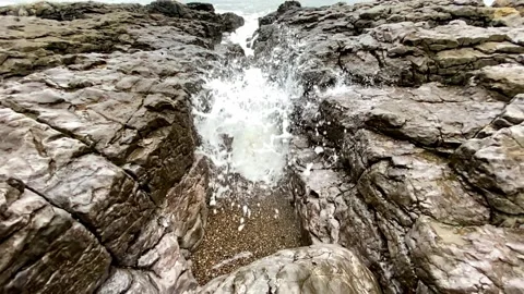 Sea crashing through gap in rocks in slow motion Stock Footage 149263859