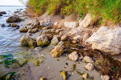 Sea erosion of rugged cliffs on sandy coastline Stock Photos