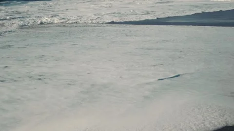 Sea foam covers the beach, leaving a soft white trail Stock Footage 337465789