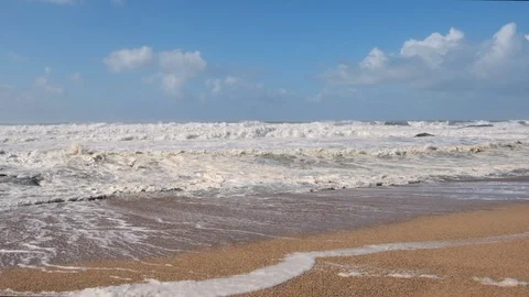 Sea foam lying on sandy beach as rough white waves break on the choppy sea Video stock 119292833