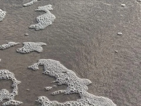 Sea foam pattern on sand Stock Photos