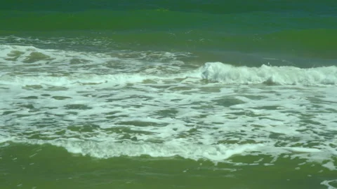 Sea foam waves roll on the sandy shore on a sunny day Stock Footage 177441490