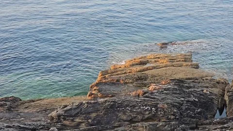 The sea gently lapping against some rocks Video stock 244384486