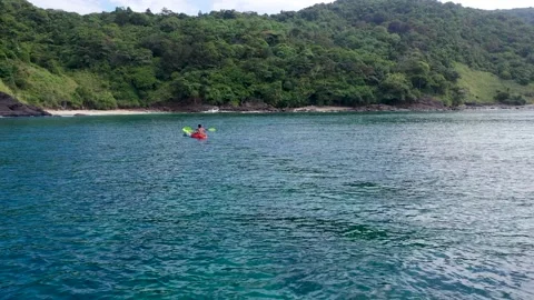 Sea kayaking. Tracking shot of kayaker paddling green and orange touring kayak Stock Footage 229720079