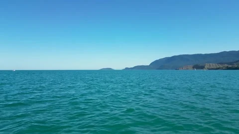 Sea-Level View of Turquoise Ocean Waters with Ilhabela Cliffs in Background – Br Vídeos de archivo 334617656