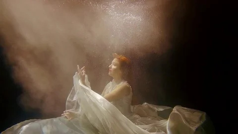 A sea nymph is under water, a lady with red hair is looking up at the light Stock Footage 84570826