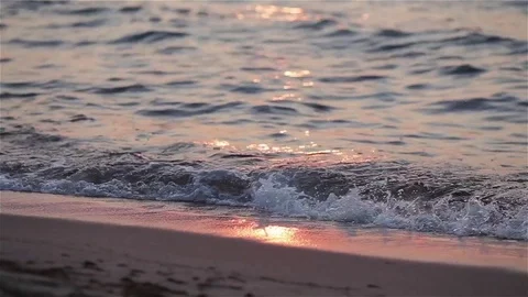 Sea ocean waves roll over beach sand at sunset close up. Pink seascape with sun Stock Footage 71315454