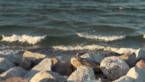 Sea or ocean waves hitting large rocks on a concrete pier during sunset. Stock Footage 137444627