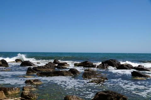 Sea panorama, waves crashing on large rocks at the water's edge Stock Photos