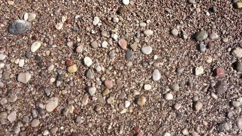 Sea pebbles and small waves in sunlight Stock Footage 107200165
