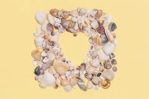 Sea shells frame with space for text on yeallow background. Stock Photos