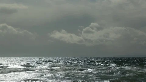 Sea Shore displaying waves and sun reflecting on the ocean with heavy clouds. 動画素材 72670004