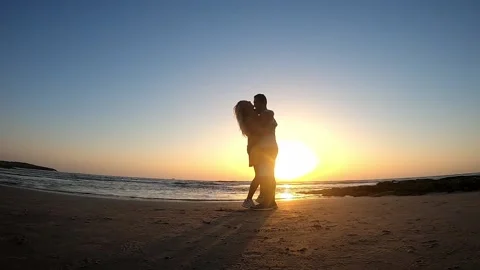 On sea shore in rays of setting sun man circles girl. Stock Footage 194993011
