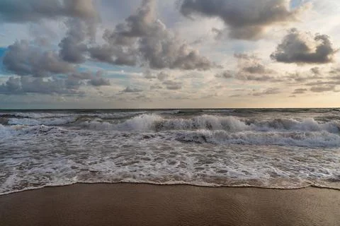 Sea splashing waves in the setting sun and beautiful cloudy sky background Stock Photos
