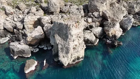 Sea stack jagged limestone boulders rising from clear turquoise water eroded Stock Footage 343594284