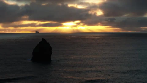 Sea Stack Silhouette at Sunset with God Rays, Iceland Aerial Stock Footage 330142729