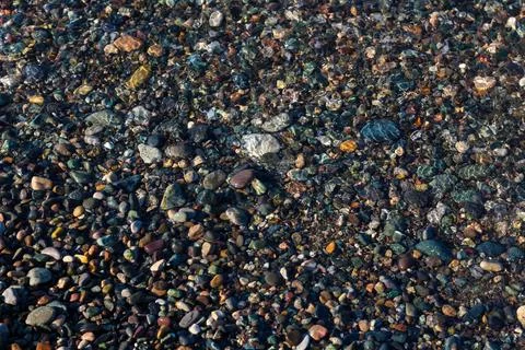 Sea stones under crystal clear water, texture of water visible on stones Foto stock